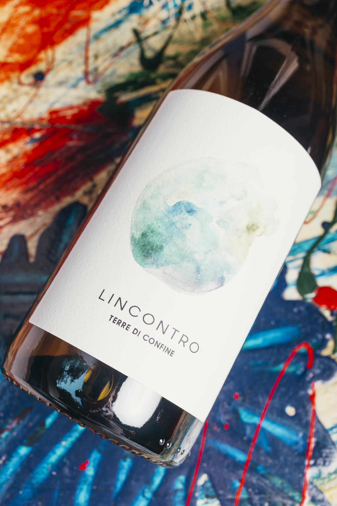 Bottiglia L'incontro Terre di Confine, vino naturale su tavolo dipinto a mano